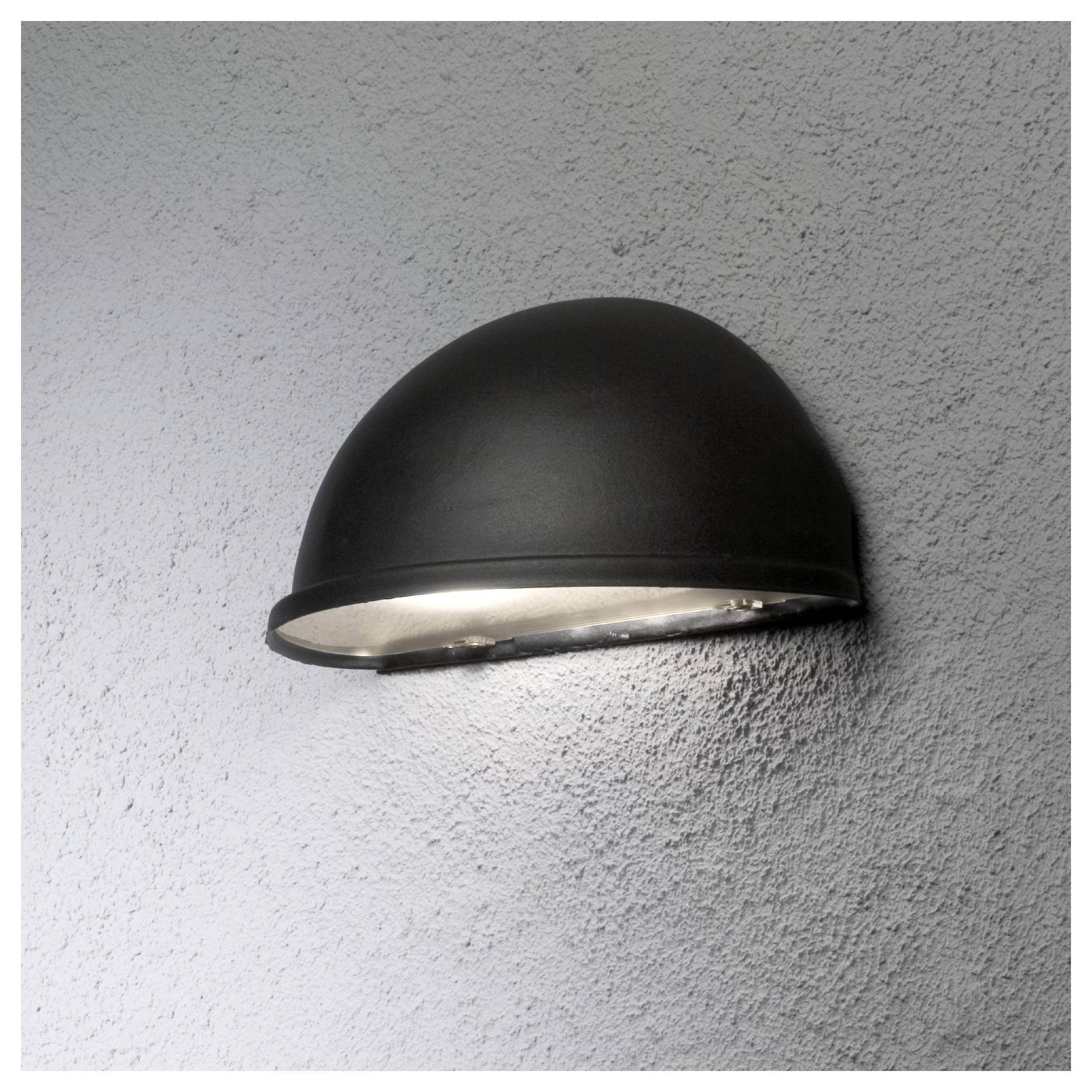 Eine an der Wand befestigte, kuppelförmige schwarze Leuchte verbreitet ein sanftes Glühen und beleuchtet eine strukturierte graue Wandoberfläche.