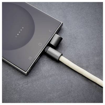 Ein Smartphone, das mit einem beigen Ladekabel auf einer dunklen Oberfläche verbunden ist. Der Bildschirm des Telefons zeigt ein teilweise aufgeladenes Batteriesymbol.