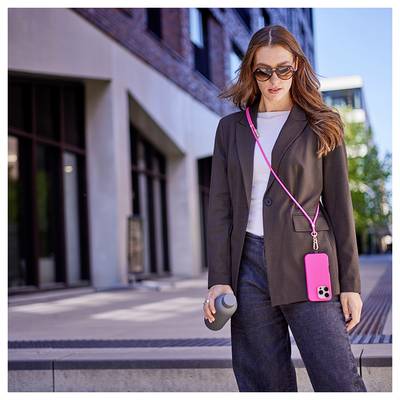 Eine Frau in einem Blazer und Sonnenbrille läuft nach draußen und hält eine wiederbefüllbare Wasserflasche. Ein rosa Handy hängt an einem Riemen um ihren Hals.