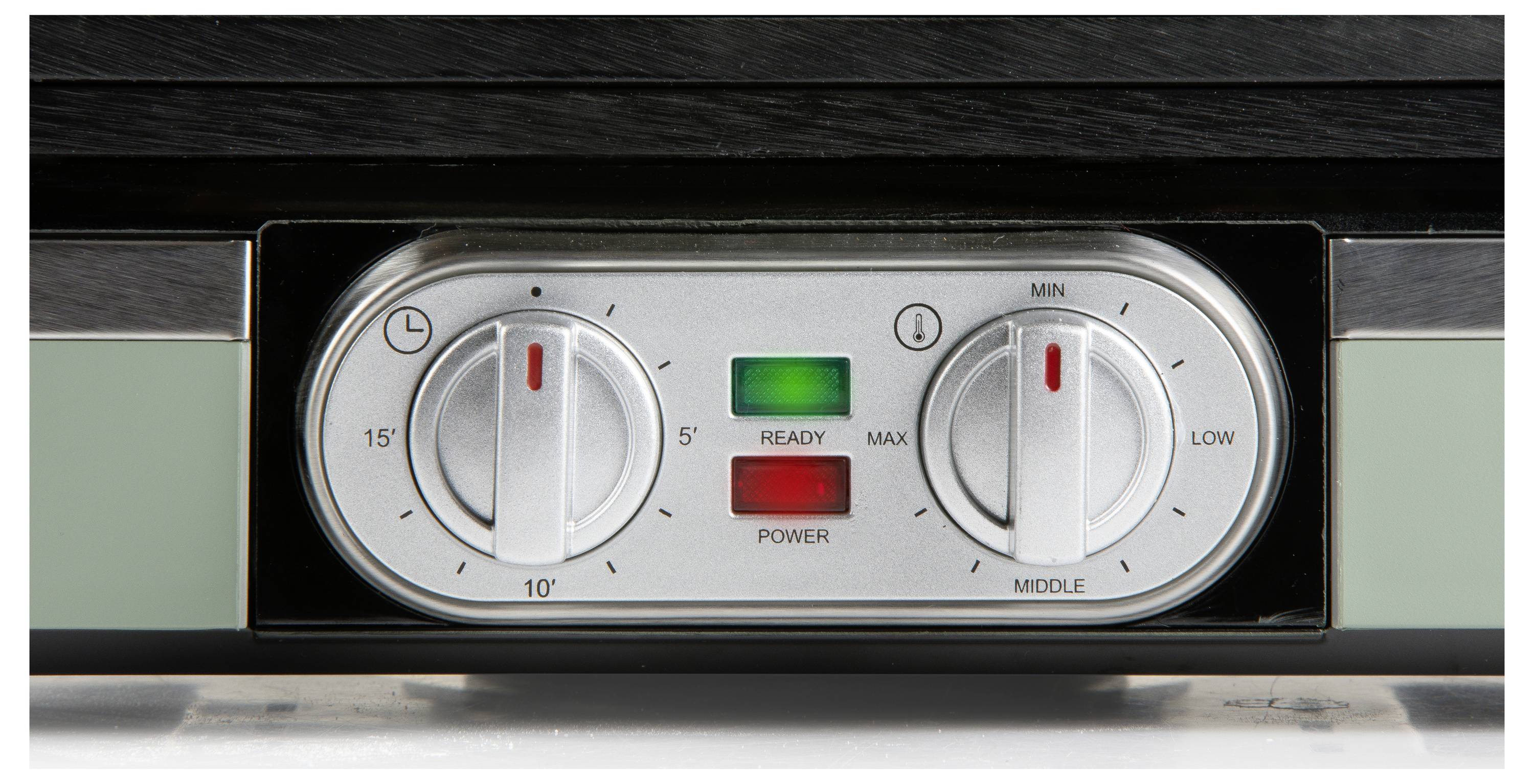 Nahaufnahme eines Geräte-Bedienfelds mit zwei Drehknöpfen. Der linke Knopf verfügt über einen Timer mit einem Bereich von 5 bis 15 Minuten. Der rechte Knopf reguliert die Temperatur von Minimum bis Maximum. Zwei Leuchten zeigen 'Bereit' und 'Strom' an.