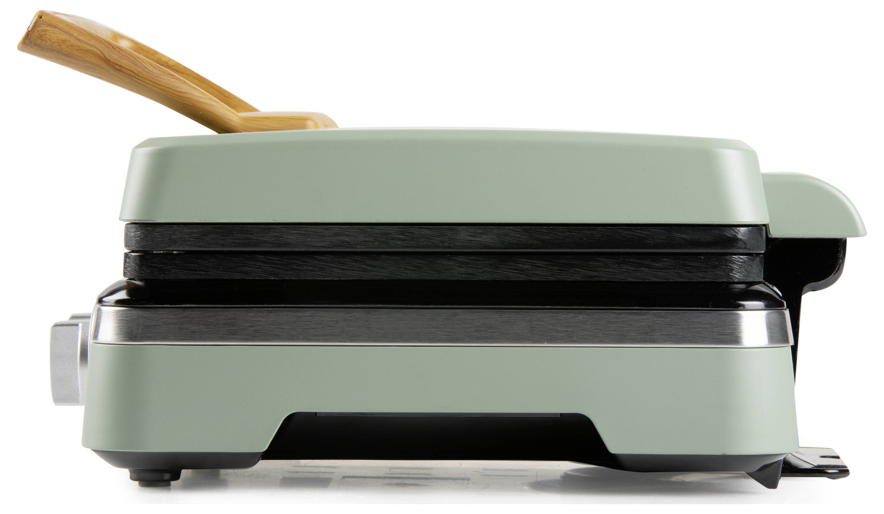 Ein geschlossener, moderner Waffeleisen mit einem Holzgriff und weicher grüner Oberfläche, von der Seite betrachtet.