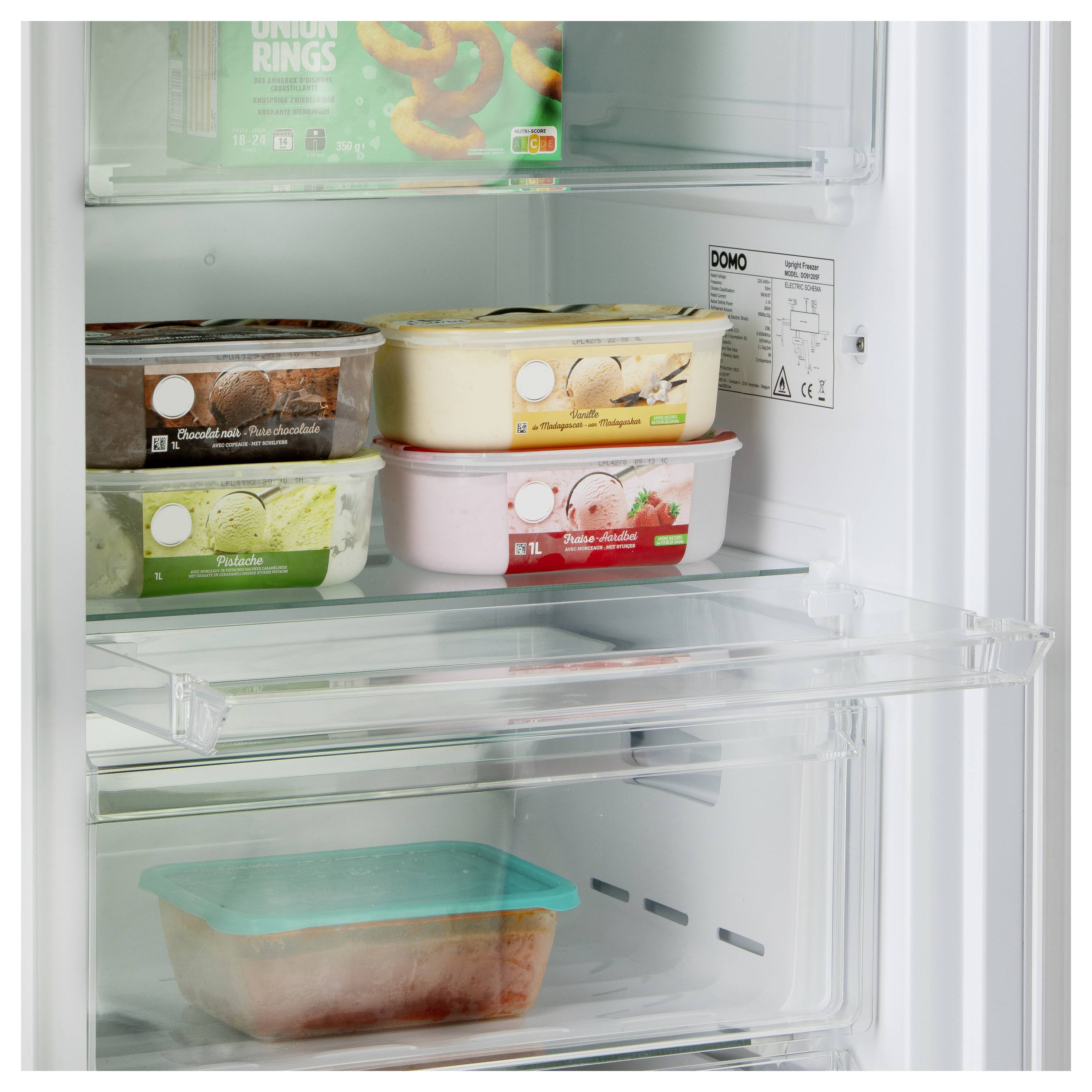 Öffne den Gefrierschrank mit vier Eisbehältern in verschiedenen Geschmacksrichtungen und einer versiegelten Schüssel auf separaten Regalen. Das obere Regal zeigt eine Packung Zwiebelringe.