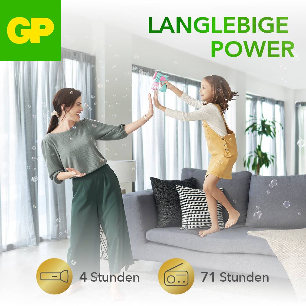 Eine Frau und ein Kind spielen mit Seifenblasen im Wohnzimmer. Oben rechts steht der Text 'Langlebige Power'. Unten sind Symbole für Akkulaufzeit.