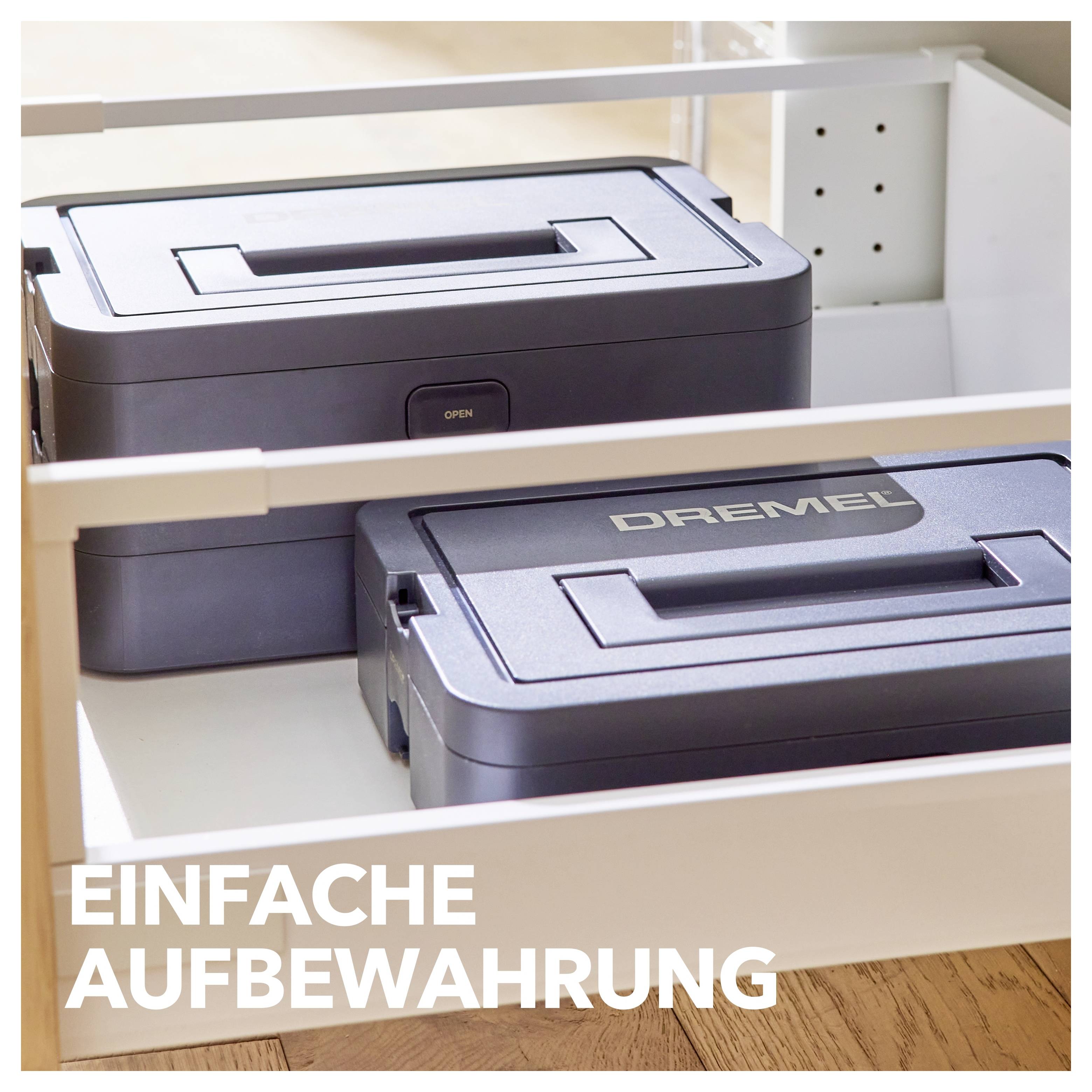 Eine graue Dremel-Werkzeugbox, sorgfältig in einer offenen weißen Schublade aufbewahrt, mit der Beschriftung 'EINFACHE AUFBEWAHRUNG' in weißer Schrift in der unteren linken Ecke.