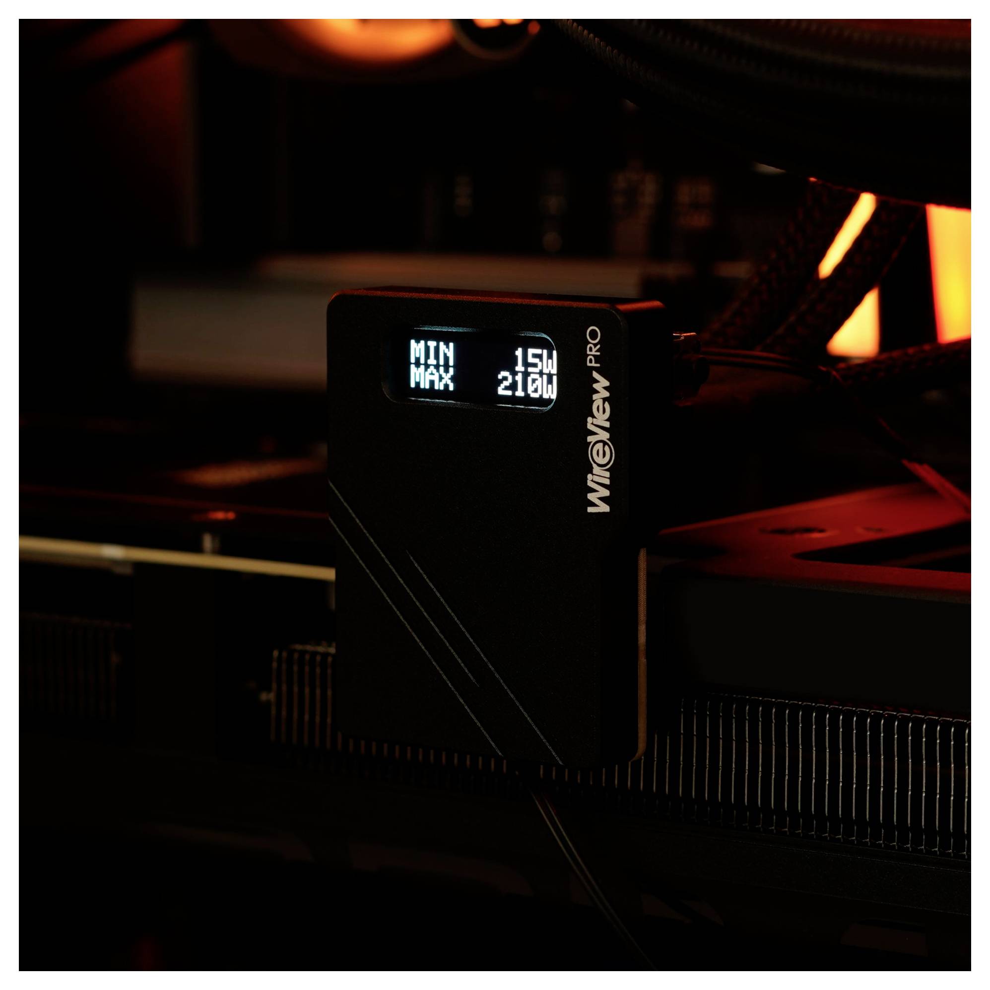 Ein kompaktes schwarzes Gerät mit einem kleinen Display, auf dem "MIN: 15W MAX: 210W" zu sehen ist, mit der Markenbezeichnung "WHEELView PRO", das mit Computerkomponenten verbunden ist.