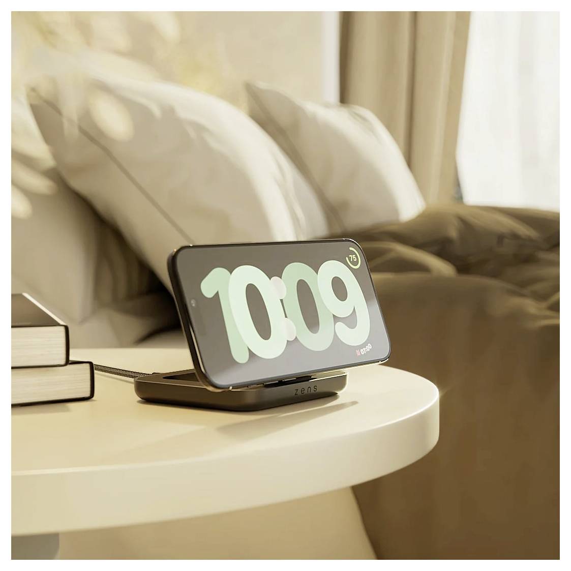 Ein Smartphone, das '10:09' auf einem drahtlosen Ladegerät neben einem Bett mit Kissen und einer beigen Decke anzeigt und einen Morgen oder eine gemütliche Atmosphäre andeutet.