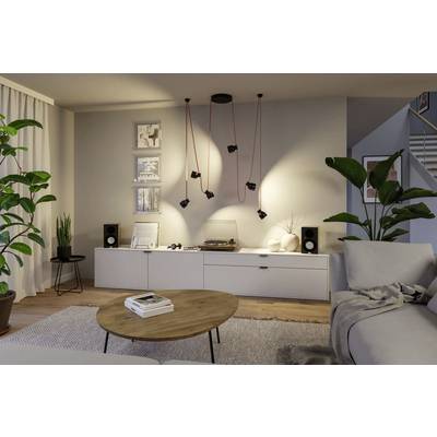 Ein moderner Wohnraum mit einem grauen Ecksofa, rundem Holzcouchtisch, Topfpflanzen, gerahmten Bildern und Audiogeräten auf einer Konsole.