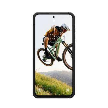 Ein Smartphone zeigt ein Bild eines Mountainbikers in der Luft über grünen Hügeln. Der Bildschirm zeigt einen Zeitstempel von '10:05 Uhr' und ein Datum von '1. November'.