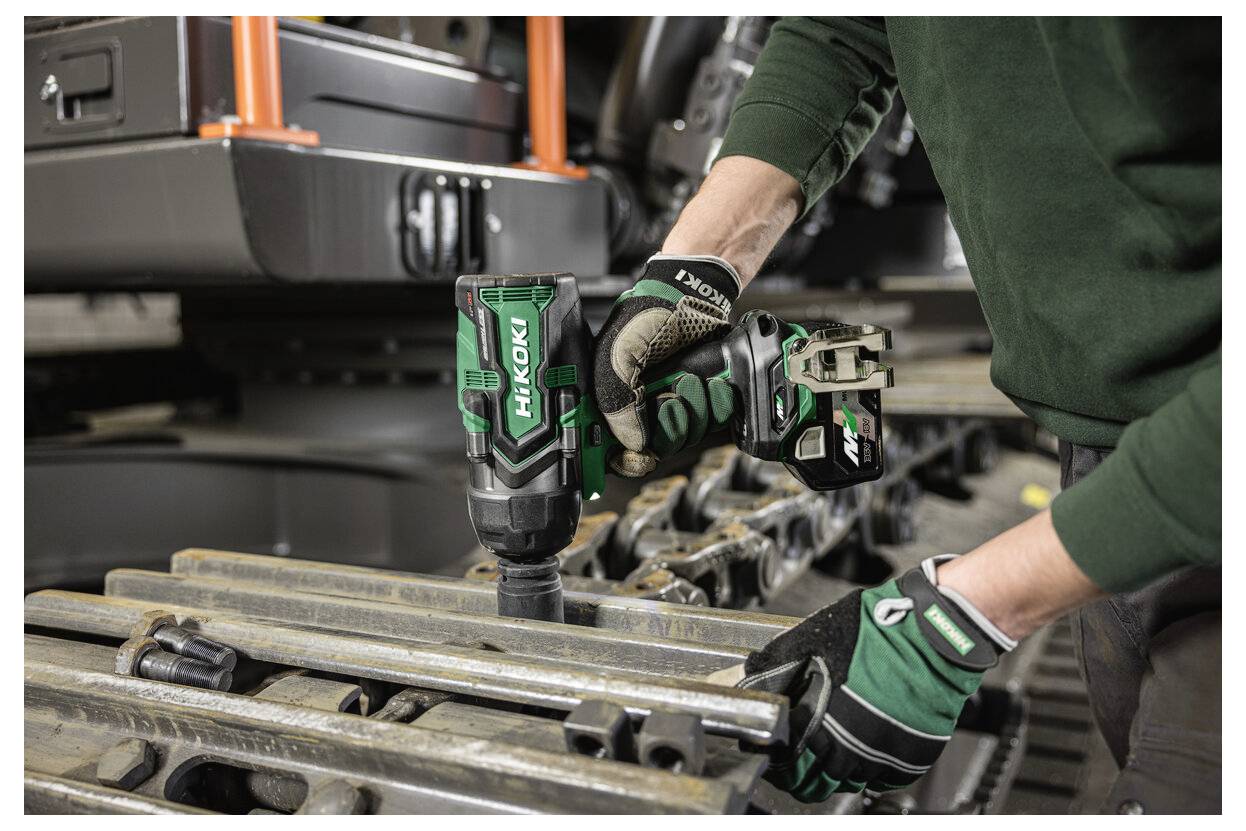 Eine Person mit Handschuhen verwendet einen Hikoki-Akku-Schlagschrauber an Metallmaschinenbauteilen und deutet damit auf einen industriellen Reparatur- oder Wartungskontext hin.