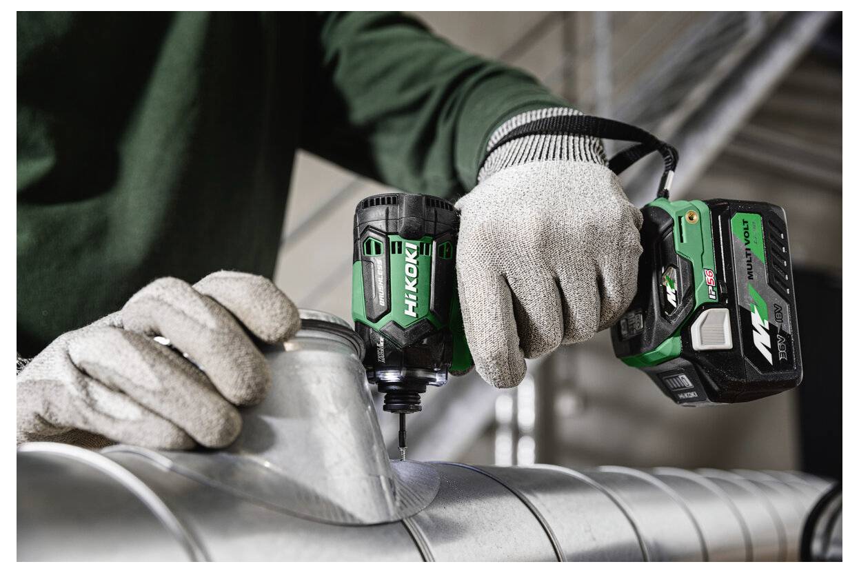 Eine Person mit Handschuhen bedient einen HiKOKI-Akku-Bohrer auf einer Metalloberfläche und konzentriert sich auf präzise Arbeit in einem industriellen Umfeld.