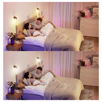 Ein Paar entspannt sich im Bett, in einem warm beleuchteten Raum mit weichen Textilien und Pflanzen, die eine gemütliche Atmosphäre schaffen.