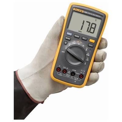 Eine Hand in einem Handschuh hält ein digitales Multimeter, das 17,8 anzeigt. Das Multimeter hat verschiedene Einstellungen und eine orangefarbene Schutzabdeckung.