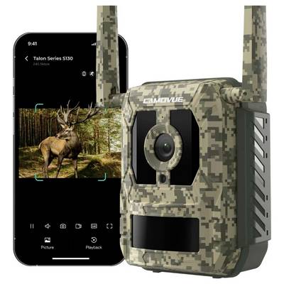 Eine getarnte Wildkamera neben einem Smartphone, das auf seinem Bildschirm ein Bild eines Hirsches im Wald zeigt.