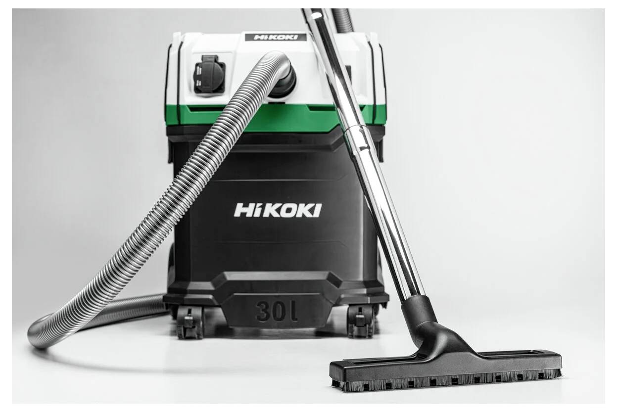 HiKOKI-Staubsauger mit großem 30-Liter-Fassungsvermögen, ausgestattet mit einem langen Schlauch und Bodenaufsatz, auf einem neutralen Hintergrund präsentiert.