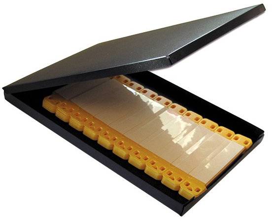 Eine offene schwarze Box, in der eine Reihe von beigen, anklippbaren Schreibtisch-Namensschildern übersichtlich in Reihen für einfachen Zugang und Aufbewahrung angeordnet sind.