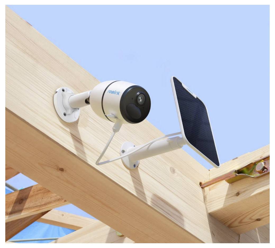 Sicherheitskamera, die an einer Holzkonstruktion befestigt ist und mit einem Solarpanel verbunden ist, vor einem klaren blauen Himmelshintergrund.