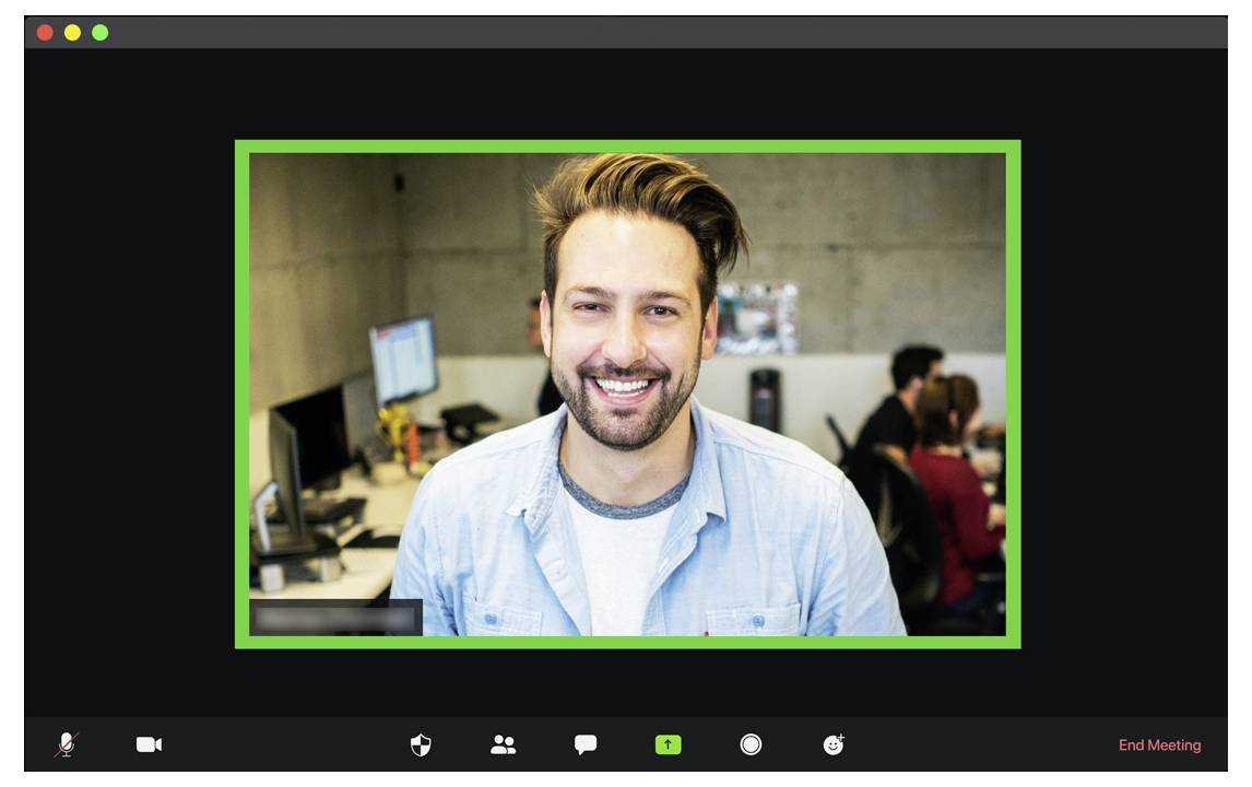 Eine Person, die während einer Videokonferenz lächelt, mit einer Büroumgebung im Hintergrund.