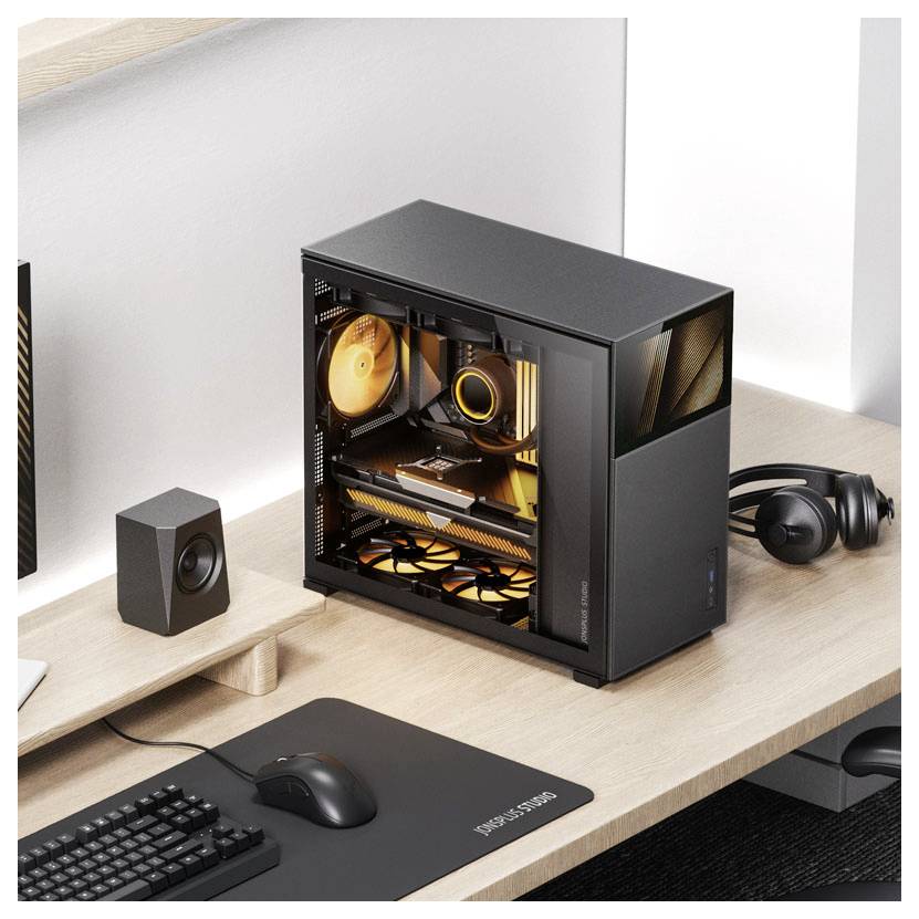 Ein Computeraufbau mit einem schwarzen Desktop-PC, dessen Kühlventilatoren orange beleuchtet sind, auf einem Holzschreibtisch platziert neben einer Maus, Tastatur und einem Lautsprecher.