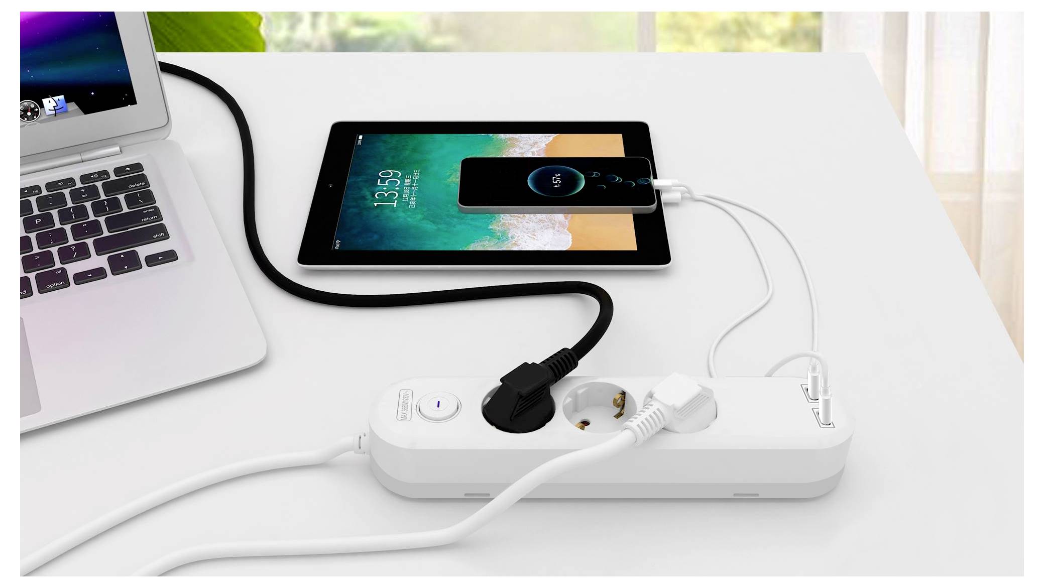 Ein Tablet und ein Smartphone laden auf einem Tisch, die mit einem Mehrfachstecker neben einem Laptop verbunden sind. Das Handy zeigt einen Ladestatus an.