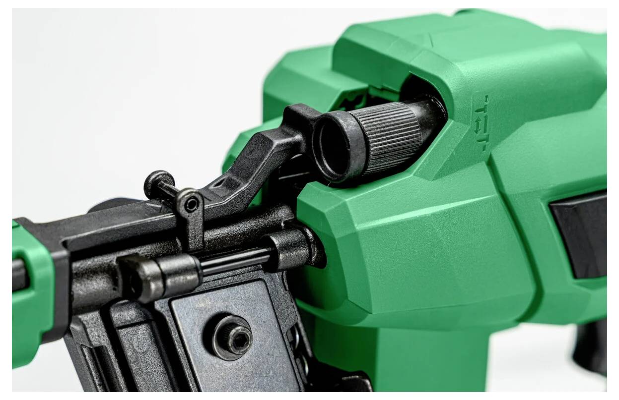 Nahaufnahme eines grünen und schwarzen mechanischen Werkzeugs mit einem Griffgriff und einer verstellbaren Komponente, möglicherweise eine Nagelmaschine oder ein Elektrowerkzeug.