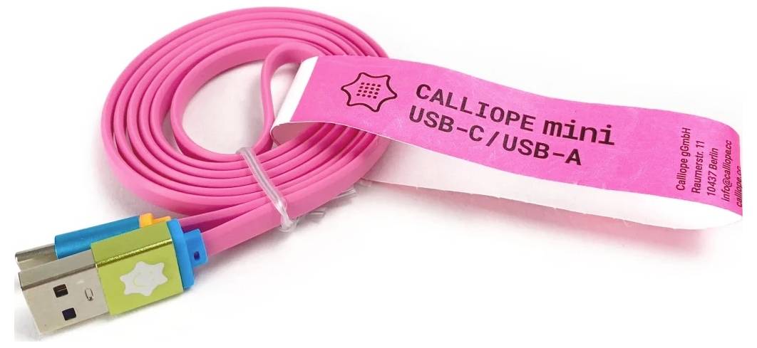 Ein rosa USB-C zu USB-A Kabel, aufgerollt mit einem Etikett mit der Aufschrift ‚CALLIOPE mini USB-C/USB-A', das auf einer weißen Oberfläche liegt.
