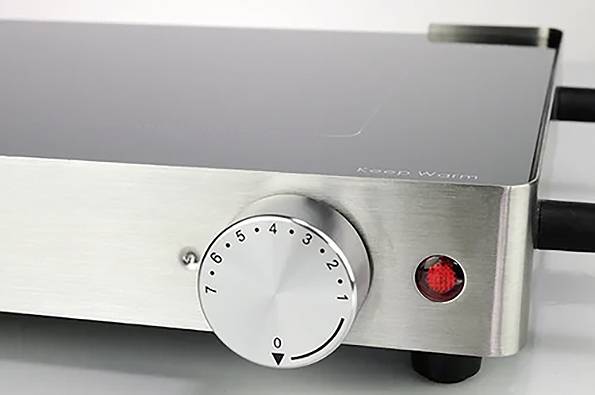 Silberner Elektroherd mit Temperatureinstellung von 0 bis 6. Rote Kontrolllampe leuchtet. Schwarze Kante am Glasrand.