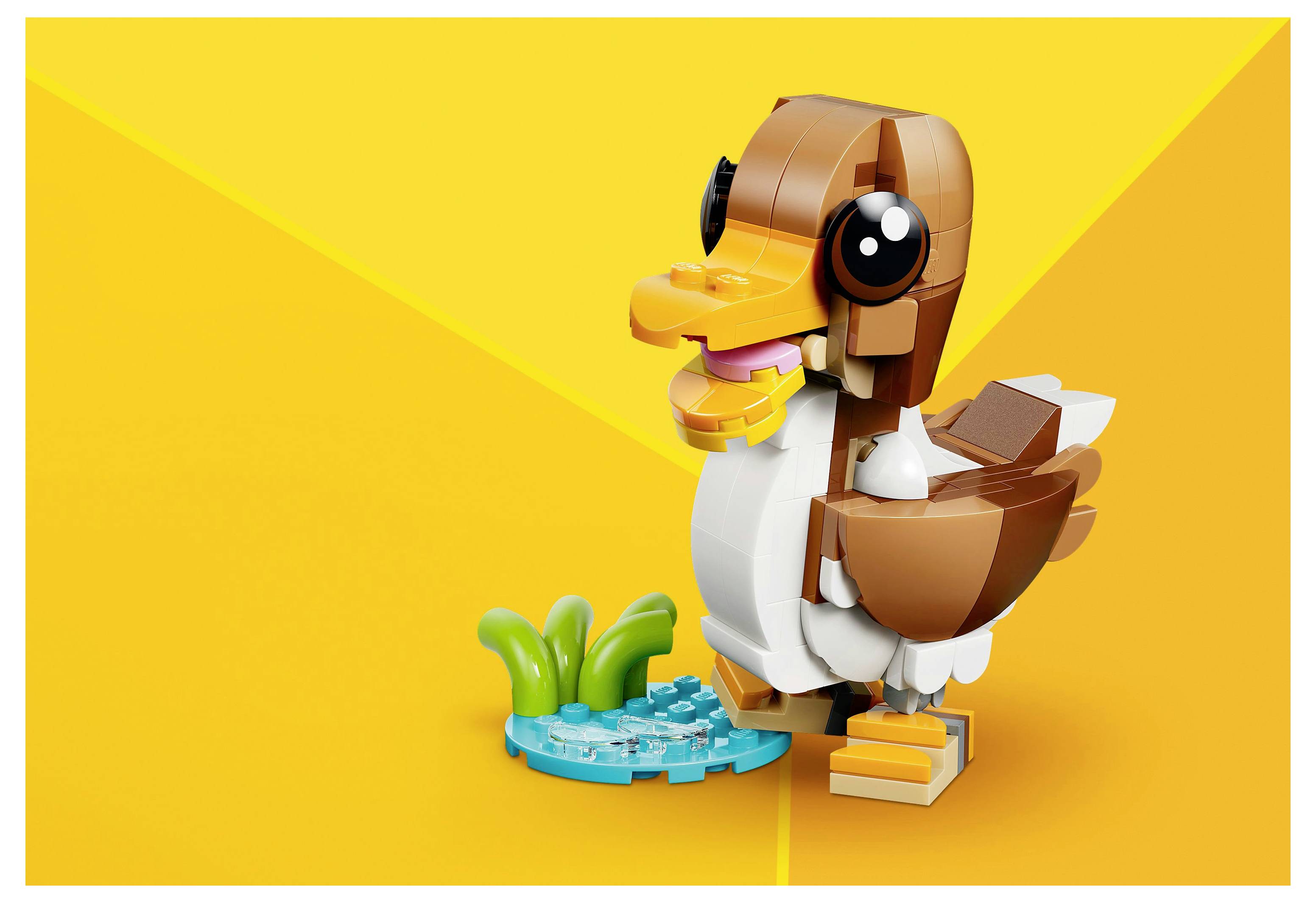 Eine LEGO-Ente mit lachendem Gesicht steht neben einem kleinen Teich mit grünen Pflanzen auf einem hellen gelben Hintergrund.