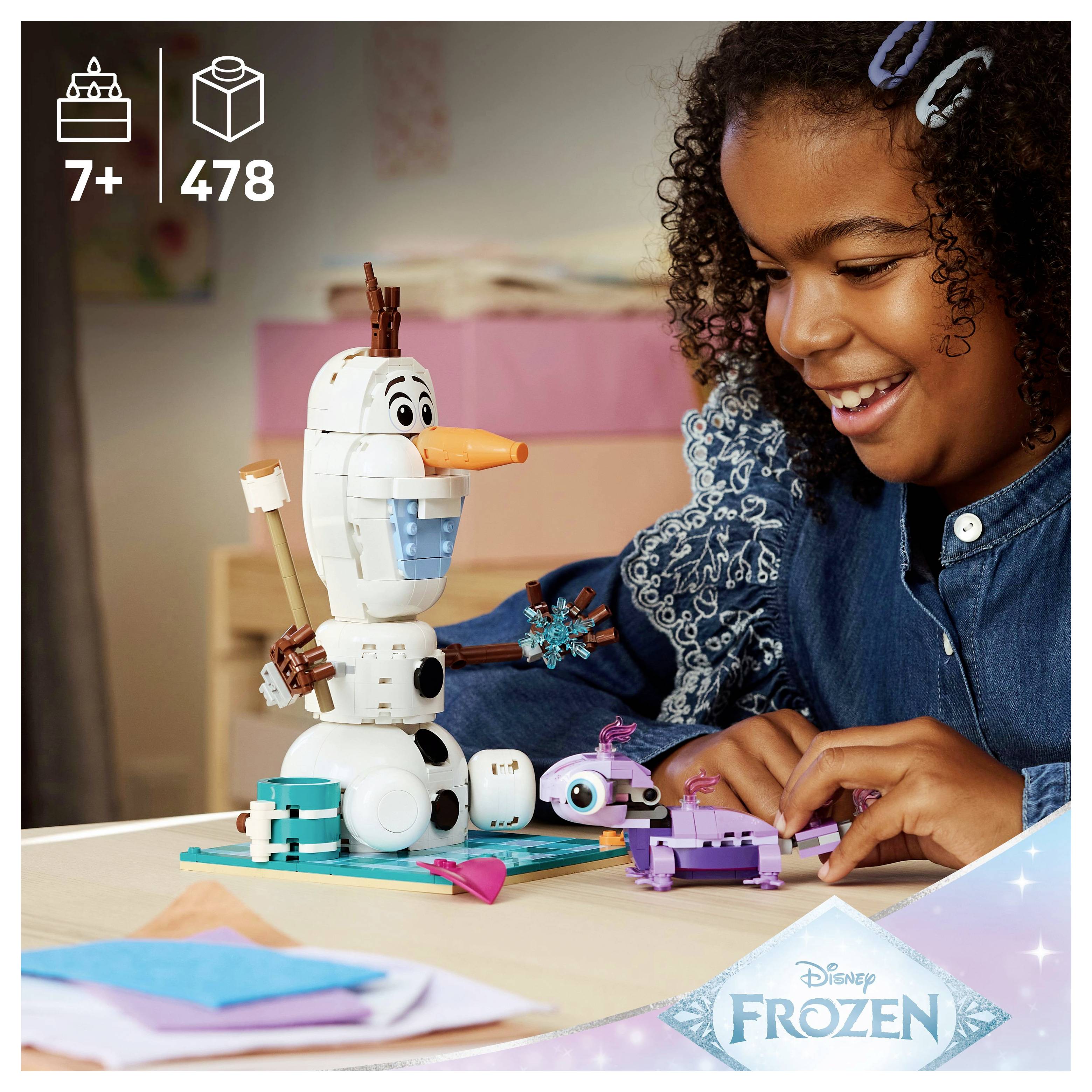 Ein Kind montiert einen 'Frozen' Spielzeugbausatz mit Olaf auf einem Tisch. Die Schachtel weist darauf hin, dass er für Kinder ab 7 Jahren geeignet ist und 478 Teile enthält.