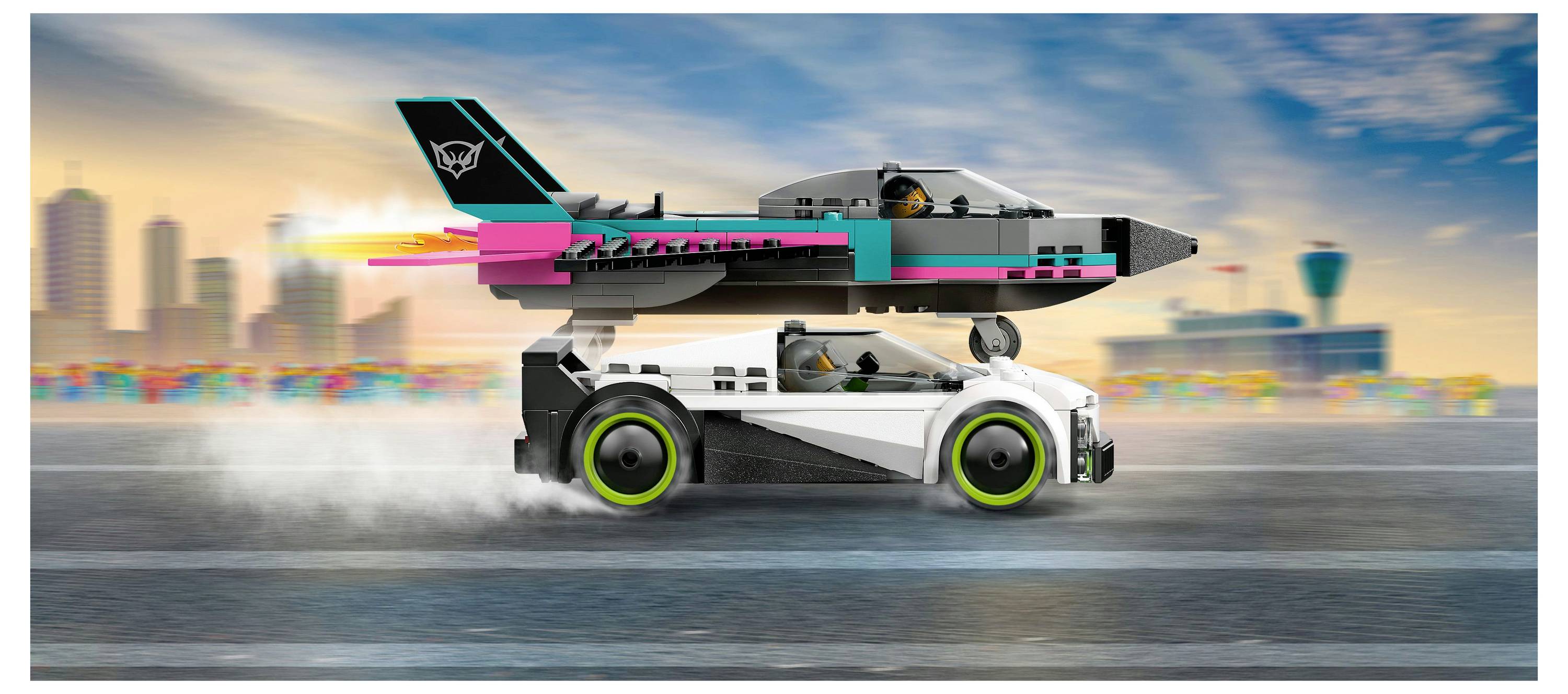 Ein weißes Sportwagen mit grünen Rädern rast auf einer Rennstrecke und trägt einen bunten Jet auf seinem Dach. Die Stadtskyline ist im Hintergrund verwischt.