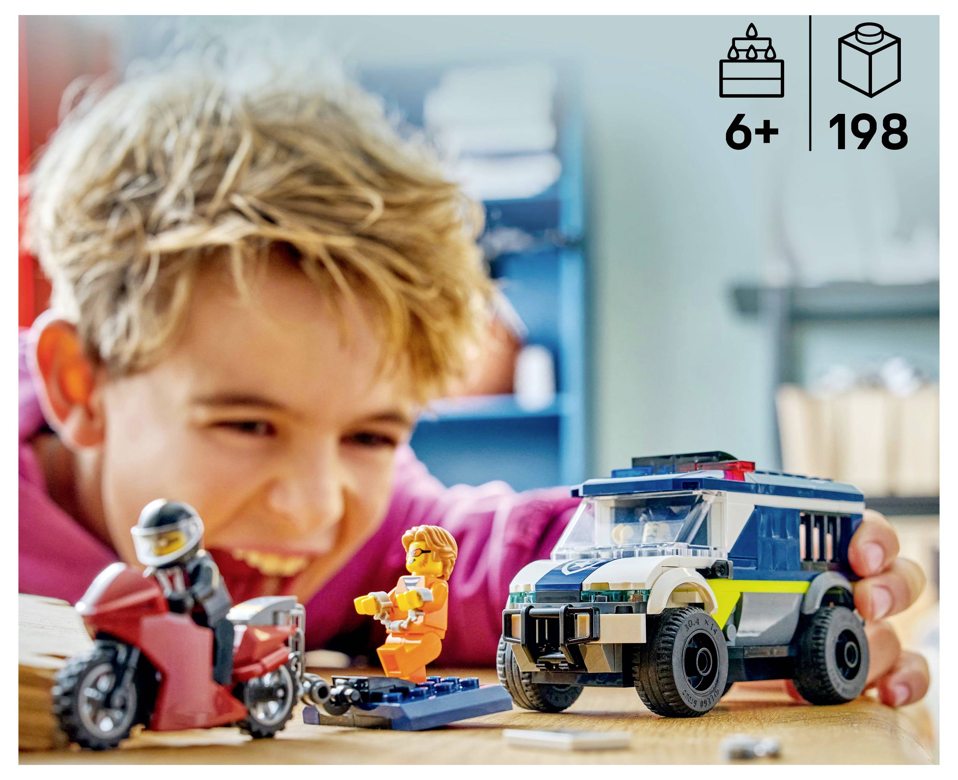 Ein Kind spielt begeistert mit einem Spielzeug-Motorrad und einem Spielzeug-Polizeiauto auf einem Tisch. Die Verpackung zeigt '6+' Alter und '198' Teile an.