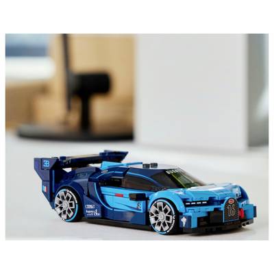 Ein blaues Spielzeug-Rennwagenmodell auf einem Tisch, das ein sportliches Design mit aerodynamischen Merkmalen und detaillierten Radstrukturen nachahmt.