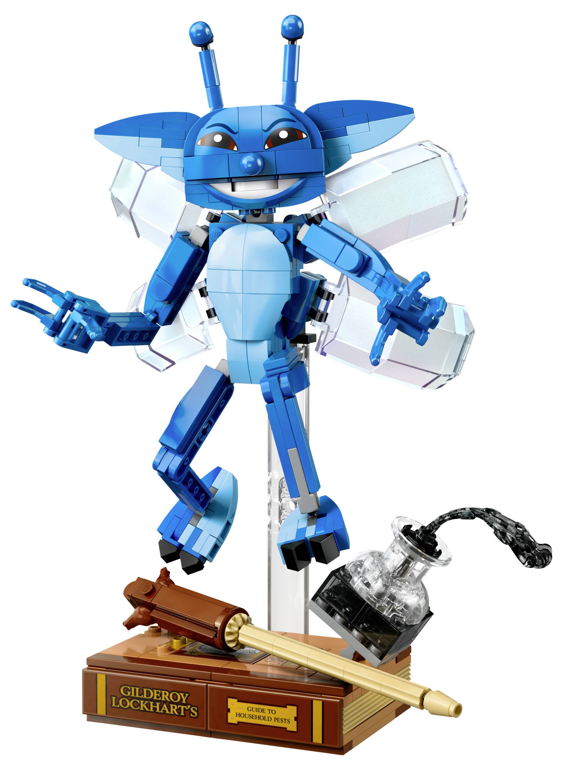 Eine blaue LEGO-Pixie-Figur mit Flügeln und Antennen posiert auf einem durchsichtigen Ständer neben einer LEGO-Tintenflasche und einer Feder auf einer braunen Basis mit der Aufschrift "Gilderoy Lockharts Kornische Kobolde".