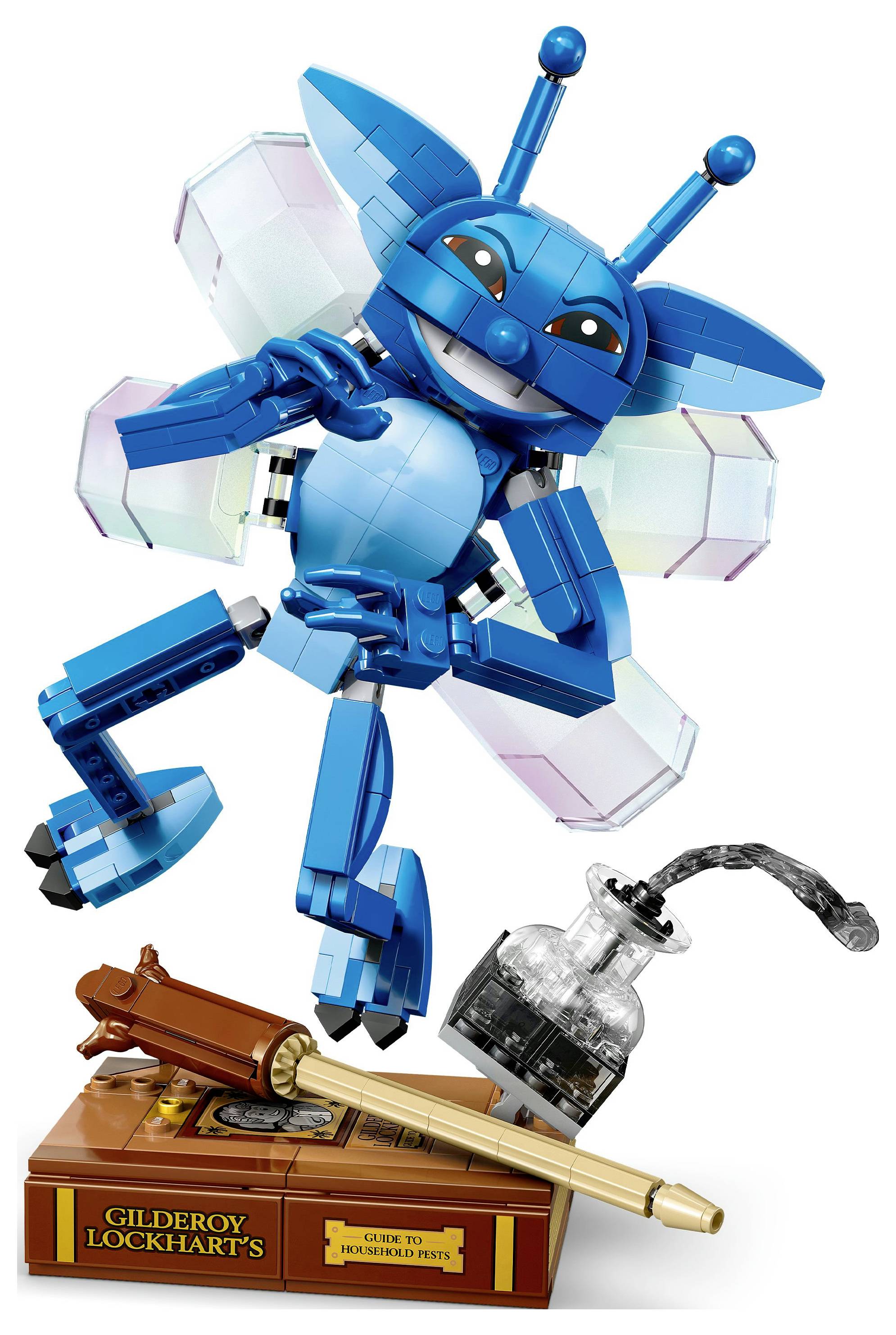Eine blaue LEGO-Kreatur mit Flügeln posiert fröhlich über einem Ständer. Der Ständer enthält eine Feder, eine Tintenflasche und eine Plakette mit der Aufschrift "Gilderoy Lockhart".