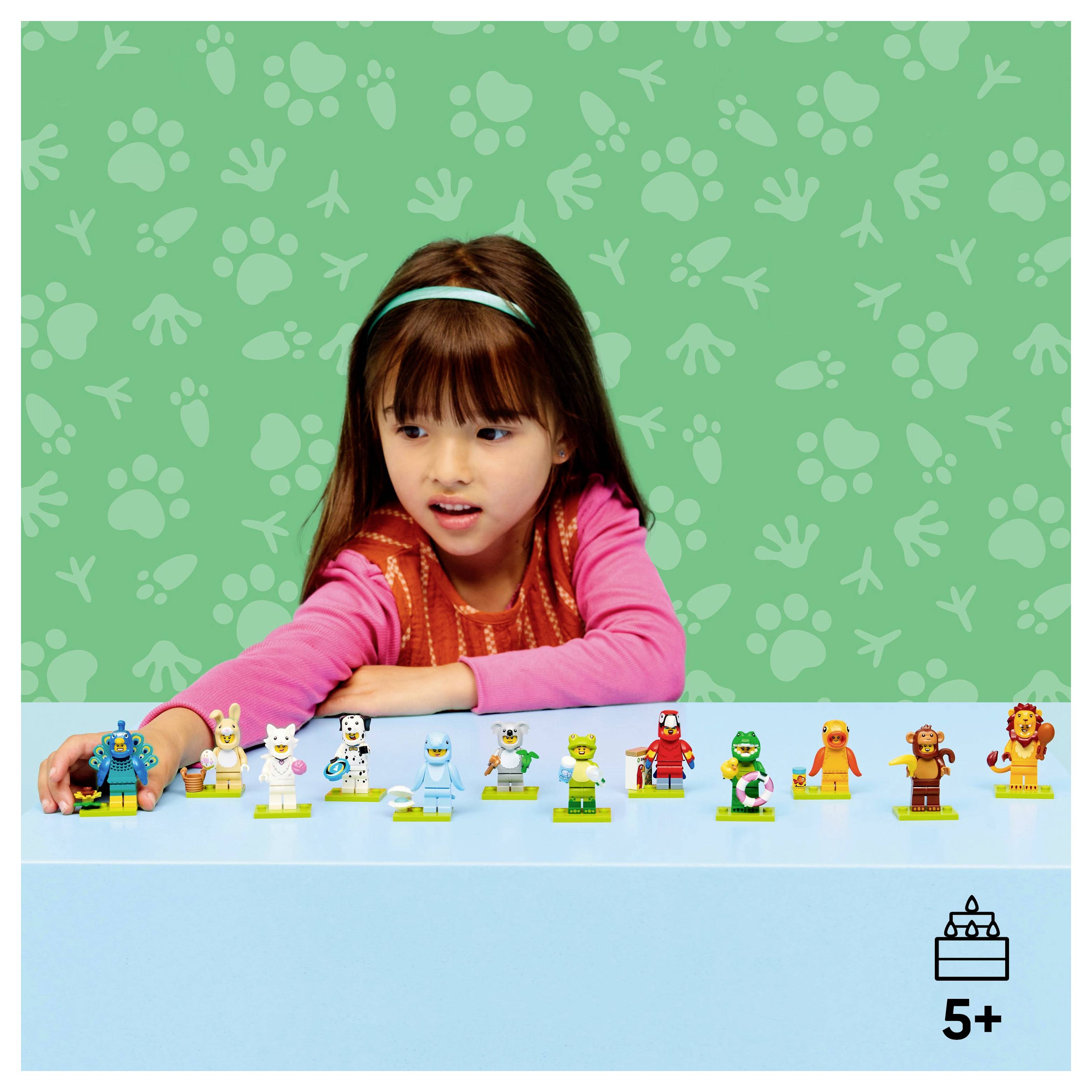 Ein Kind in einem rosa Outfit sitzt an einem blauen Tisch mit tierisch gestalteten Spielfiguren, die aufgereiht sind. Der Hintergrund zeigt Tier-Pfotenabdrücke und Fußspurmuster. Geeignet für Kinder ab 5 Jahren.