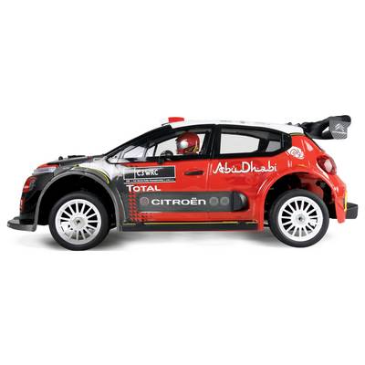 Ein Spielzeug-Rallyeauto-Modell in Rot, Schwarz und Weiß zeigt einen Fahrer mit Helm. Es trägt Sponsorenlogos, darunter ‚Abu Dhabi' und ‚Total'.