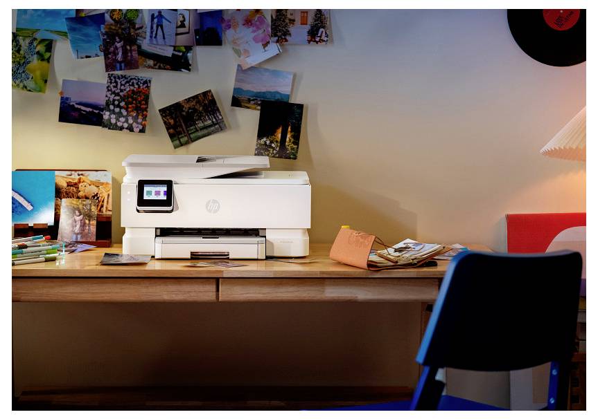 Ein Heimarbeitsplatz-Schreibtisch mit einem Drucker, umgeben von verstreuten Fotos und Papieren, unter sanftem Lampenlichts.