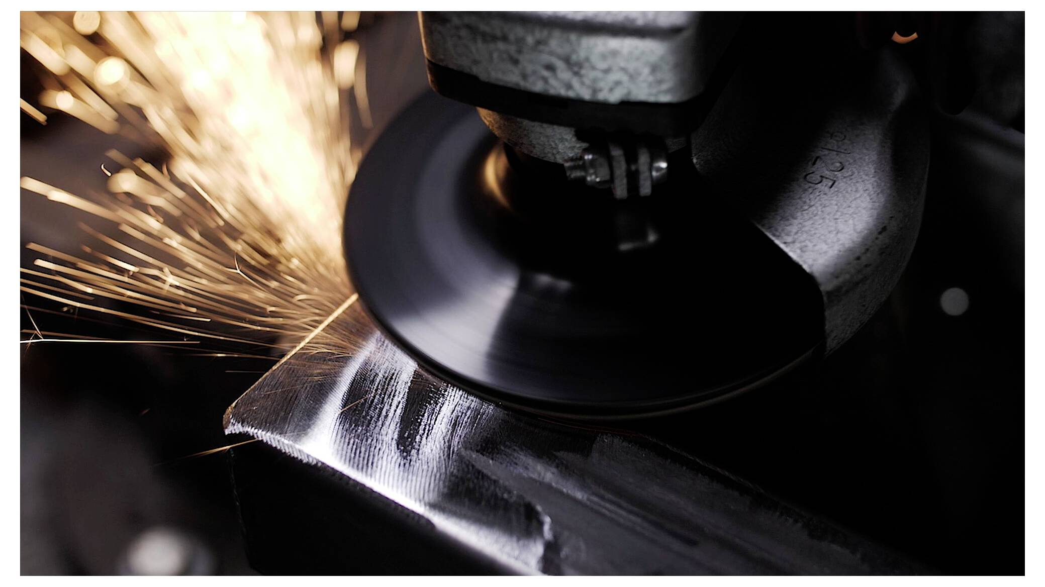 Eine Schleifmaschine sendet helle Funken aus, während sie ein Metallstück glättet und damit präzise Bearbeitung in einem industriellen Umfeld hervorhebt.