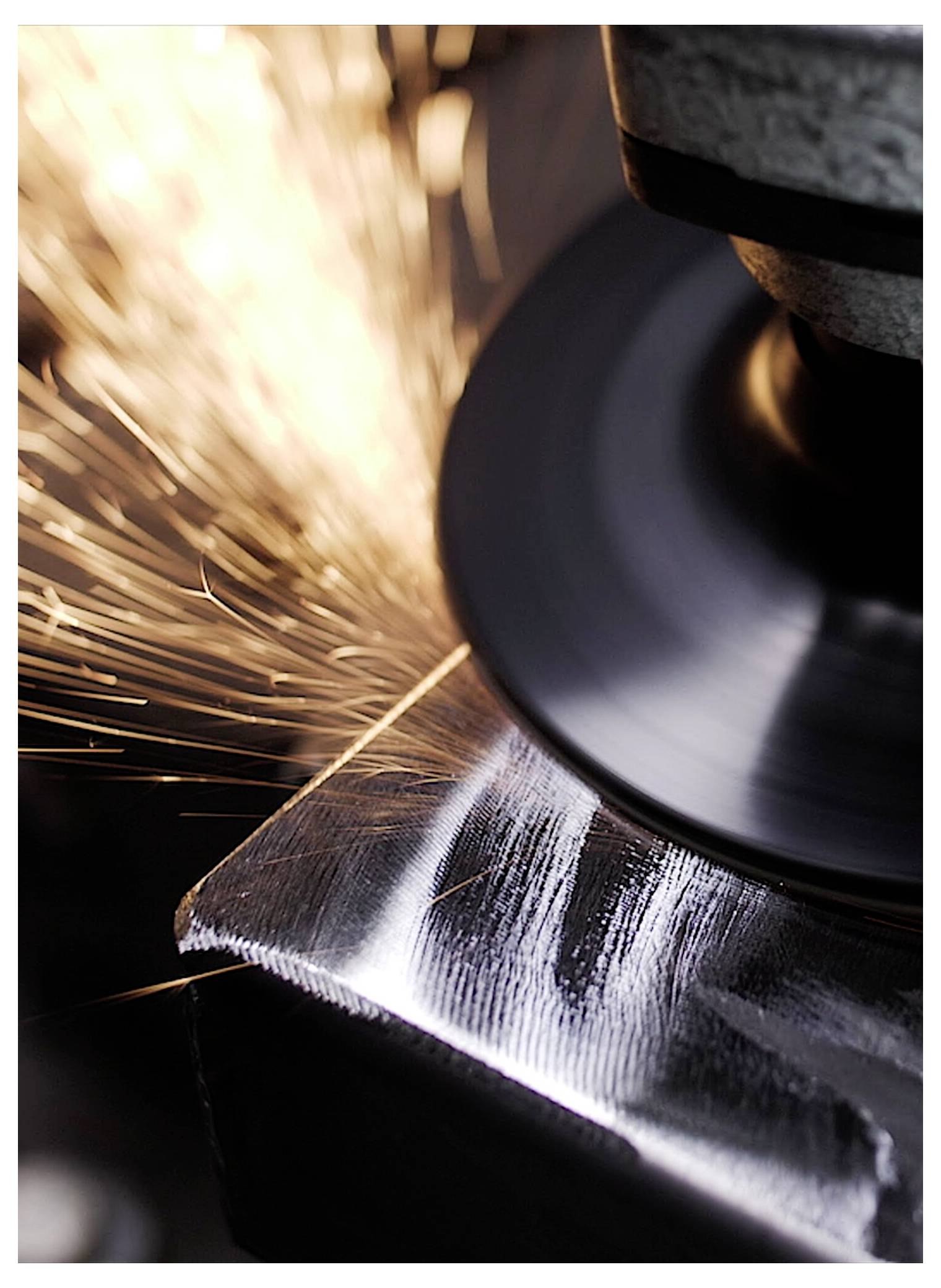 Eine Nahaufnahme eines Schleifrades, das Funken ausstößt, während es eine Metalloberfläche poliert und dabei industrielle Präzision und Handwerkskunst hervorhebt.