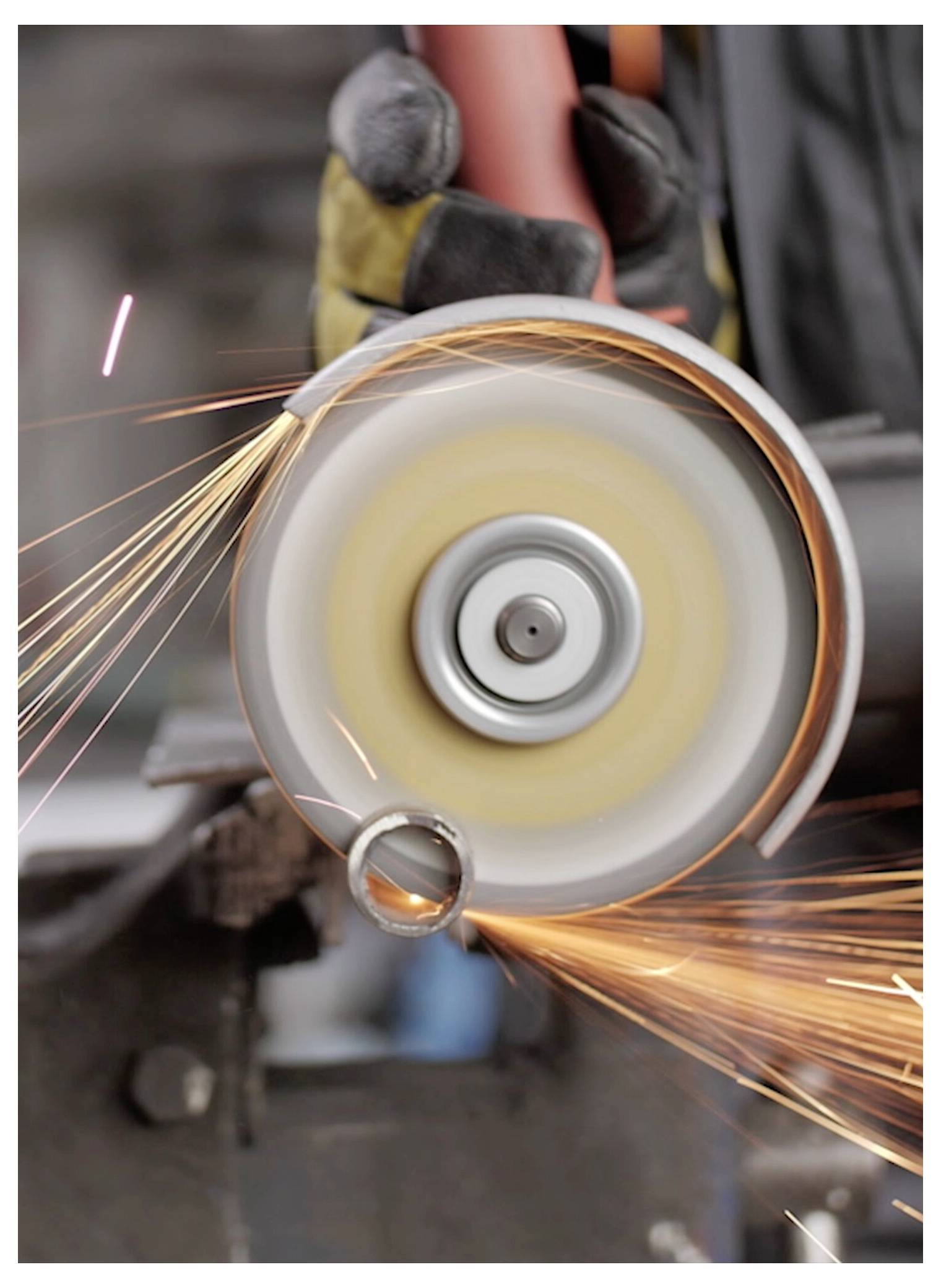 Eine Person bedient einen Kreisschleifer und erzeugt Funken beim Formen von Metall in einer Werkstatt und unterstreicht dabei die Präzision der Metallbearbeitung.