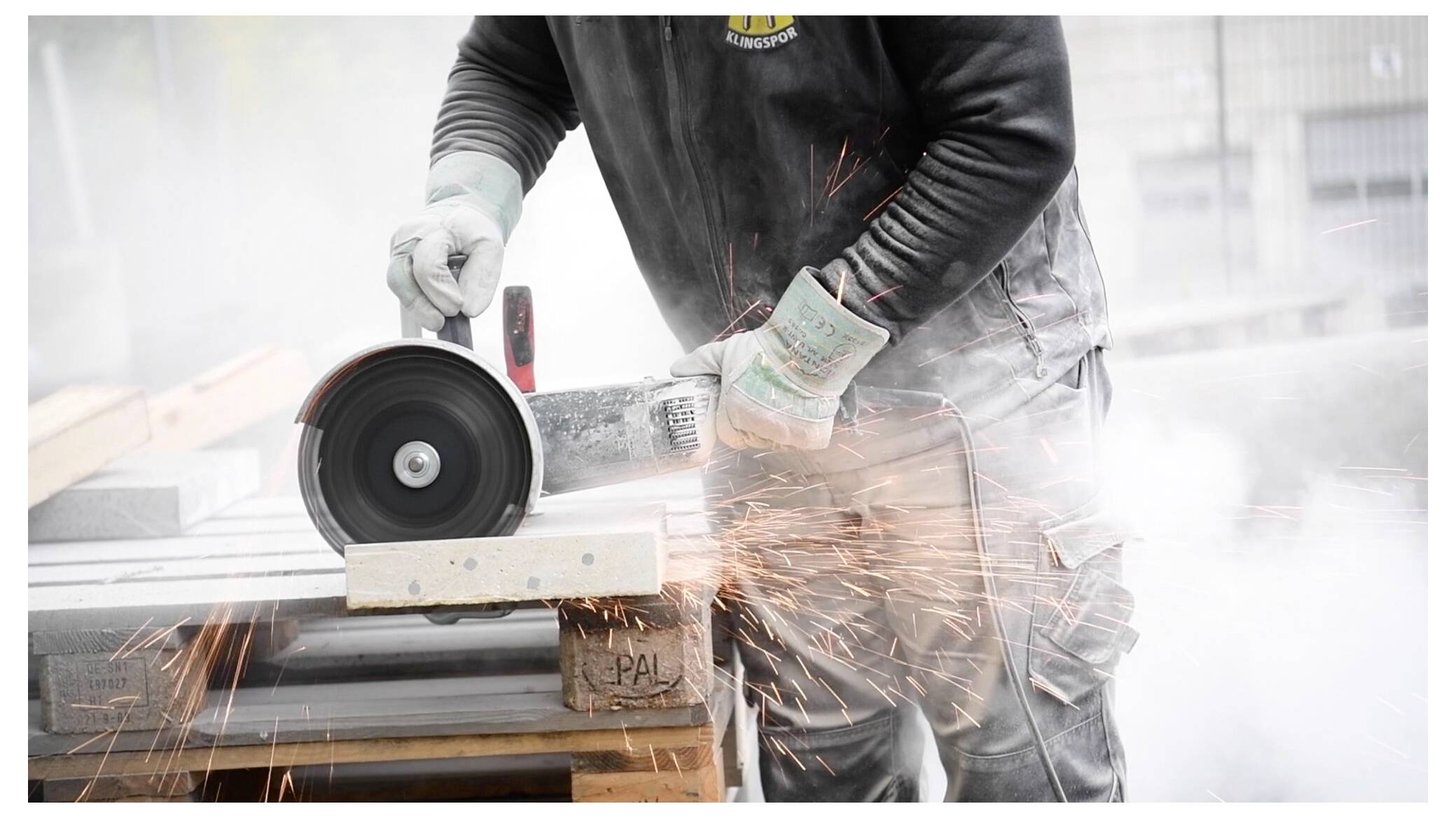 Arbeiter schneidet ein Metallstück mit einer Kreissäge und erzeugt Funken. Trägt Schutzhandschuhe und Schutzkleidung und betont damit die Sicherheit bei Bauarbeiten.