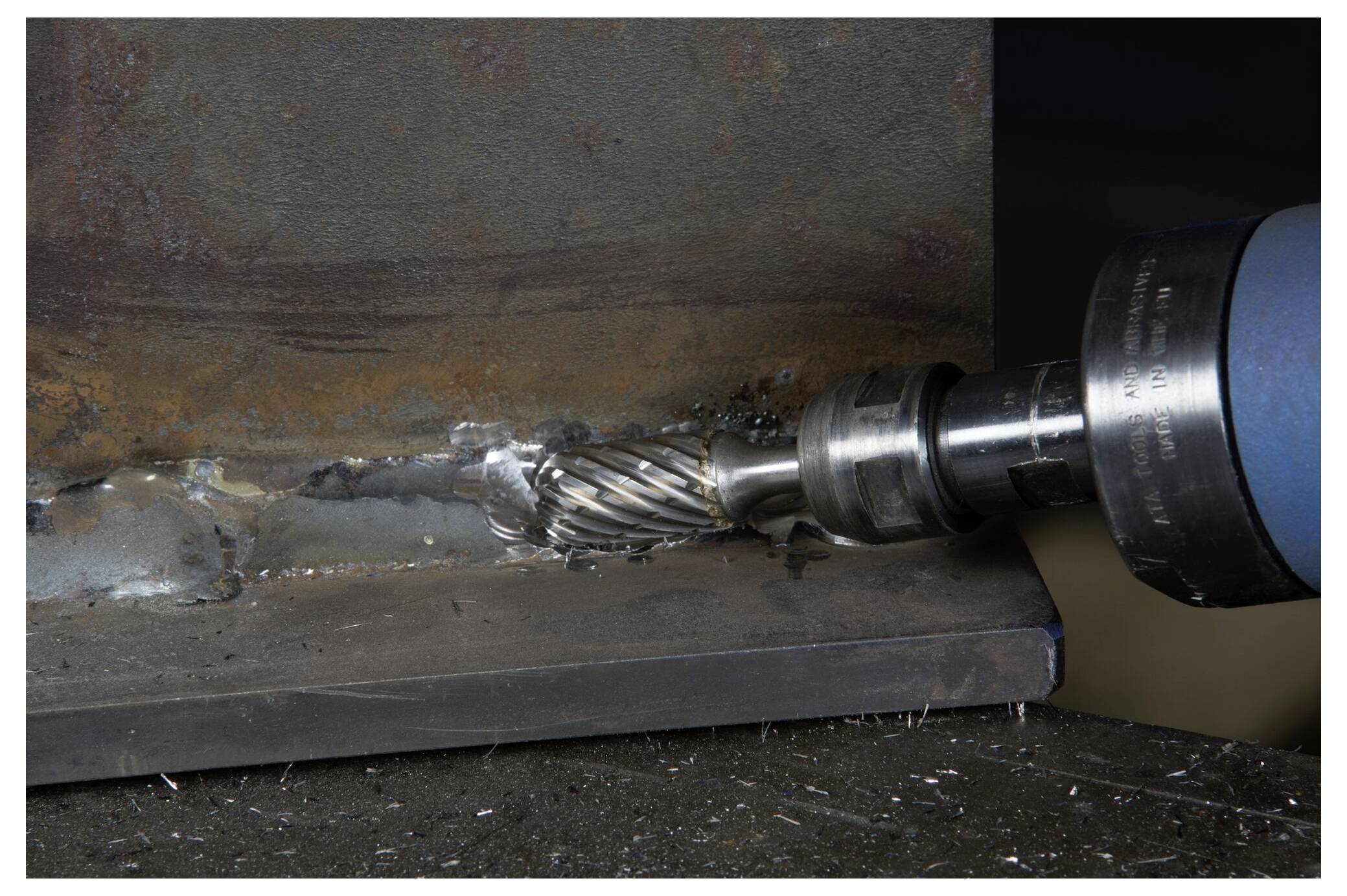 Eine Rotationsmaschine mit Fräsaufsatz poliert eine geschweißte Metallfuge auf einer Stahloberfläche.