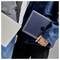 Zwei Personen, die geschlossene Laptops halten, einer mit einem Apple-Logo, tragen lässige Jacken.