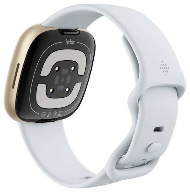 Eine Smartwatch mit goldfarbenem Gehäuse und hellgrauem Band, deren Unterseite mit Sensoren zu sehen ist. Der Markenname 'fitbit' ist sichtbar.