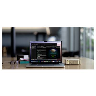 Ein Laptop auf einem Schreibtisch zeigt Softwarecode und eine Benachrichtigung "Paket installiert". In der Nähe befinden sich eine Brille, ein Ordner und eine kleine Box.