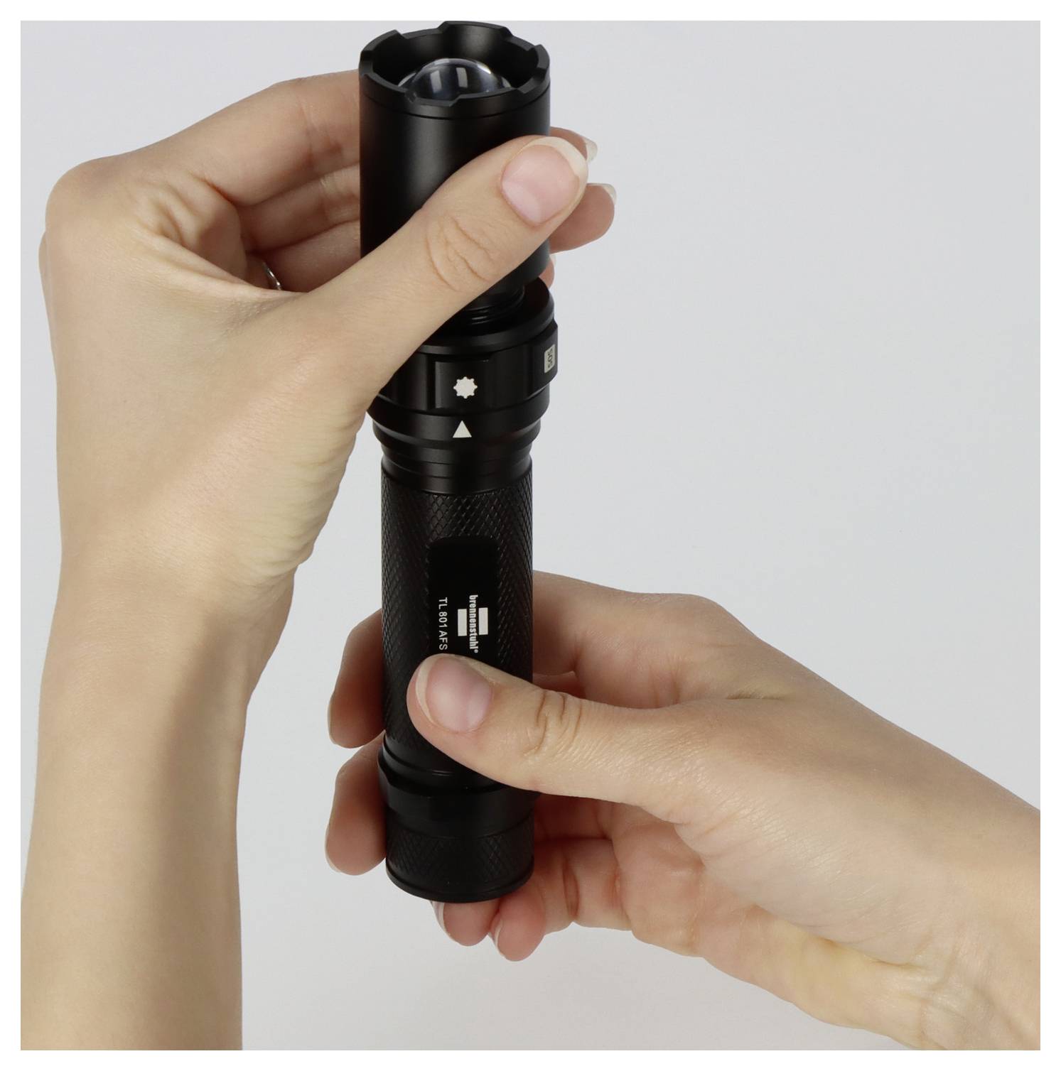 Zwei Hände, die eine schwarze Taschenlampe halten und deren Einstellungen justieren.