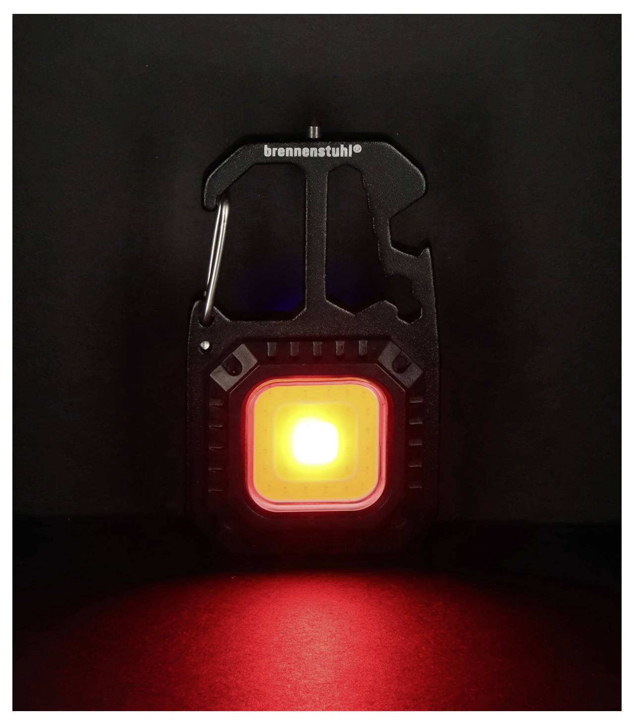 Eine schwarze LED-Leuchte in Karabinerform mit einem leuchtend roten quadratischen Schein, mit der Markenbezeichnung 'brennenstuhl', vor einem dunklen Hintergrund.