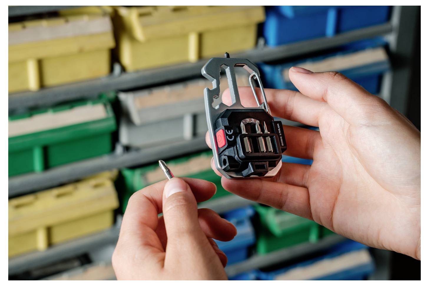 Hände, die ein Fahrradpedal mit Cleats halten, eine kleine Schraube wird eingestellt. Bunte Aufbewahrungsboxen im Hintergrund.