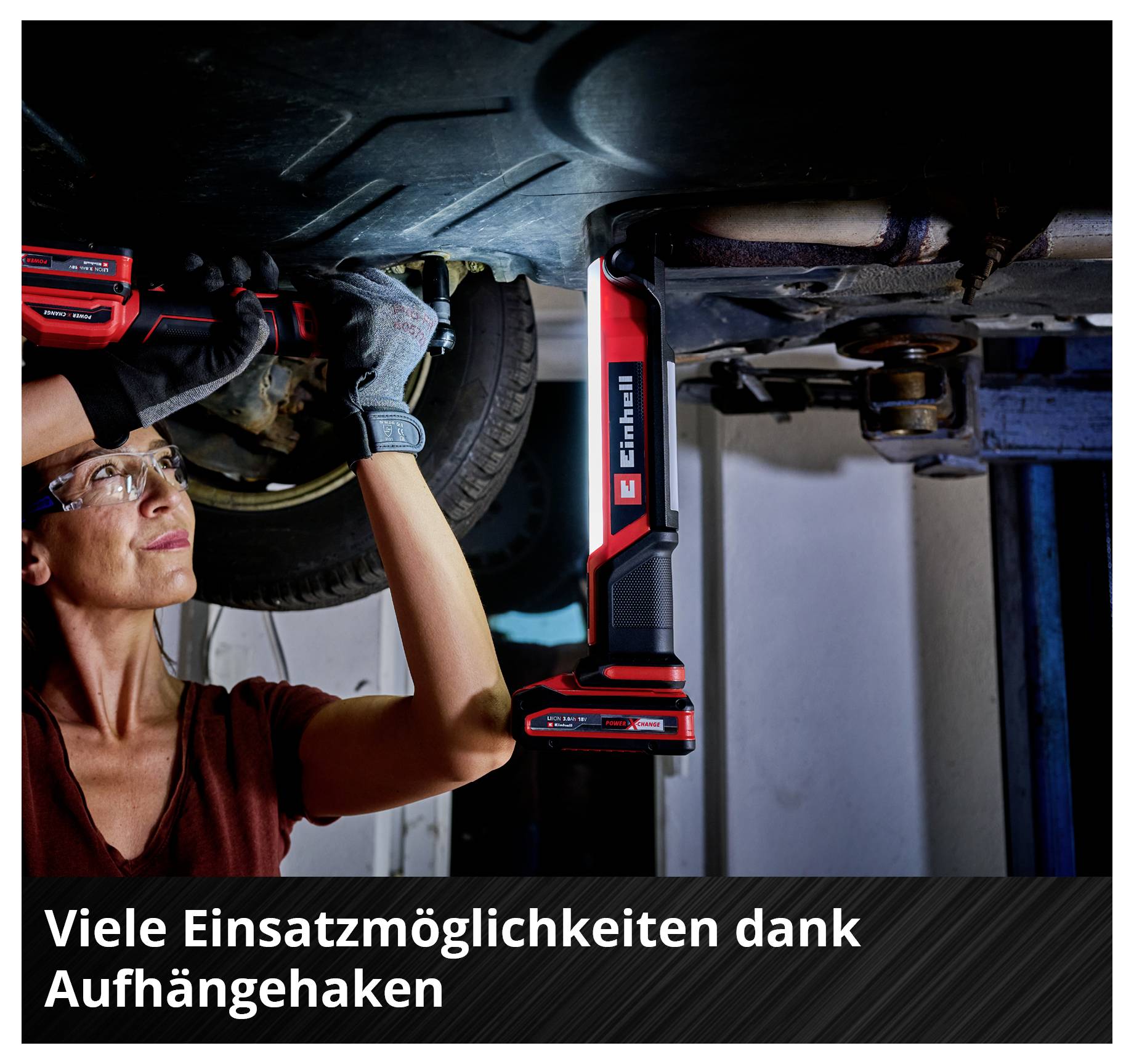 Frau repariert Auto von unten mit roter Einhell Lampe. Text auf Bild: 'Viele Einsatzmöglichkeiten dank Aufhängehaken'.