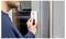 Eine Person verwendet einen Fingerabdruckscanner an einer Tür, höchstwahrscheinlich um einen gesicherten Bereich zu entsperren oder zu betreten. Der Fokus liegt auf der Hand und dem Gerät.