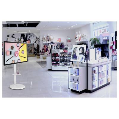 Das Interieur eines modernen Kosmetikgeschäfts mit verschiedenen Make-up-Displays, einem digitalen Bildschirm, der Beautypprodukte zeigt, und Mannequins im Hintergrund.
